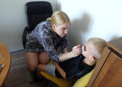 Wychowanka maluje farbami twarz dziecku3